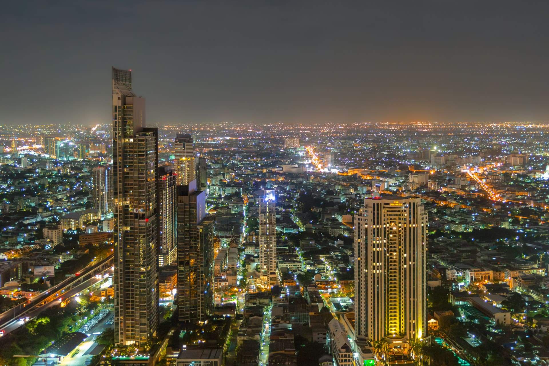 Neon-lit Bangkok street with tuk-tuks at night
